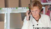 Bundeskanzlerin Angela Merkel (CDU) horcht am Donnerstag (20.08.2009) mit aufgesetztem Kopfhörer den Ansagen eines Bandes mit Hinweisen zum Zusammenstellen einer Einkaufsliste bei der Logistik-Firma Fiege in Greven (Kreis Steinfurt). Merkel besucht das Unternehmen auf ihrer Wahlkampftour. Foto: Friso Gentsch dpa/lnw +++(c) dpa - Report+++