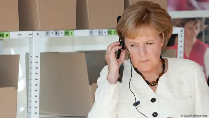Bundeskanzlerin Angela Merkel (CDU) horcht am Donnerstag (20.08.2009) mit aufgesetztem Kopfhörer den Ansagen eines Bandes mit Hinweisen zum Zusammenstellen einer Einkaufsliste bei der Logistik-Firma Fiege in Greven (Kreis Steinfurt). Merkel besucht das Unternehmen auf ihrer Wahlkampftour. Foto: Friso Gentsch dpa/lnw +++(c) dpa - Report+++