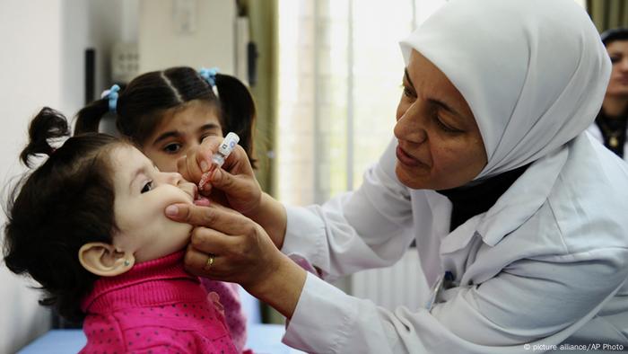 Mulher vacinando criança com conta-gotas