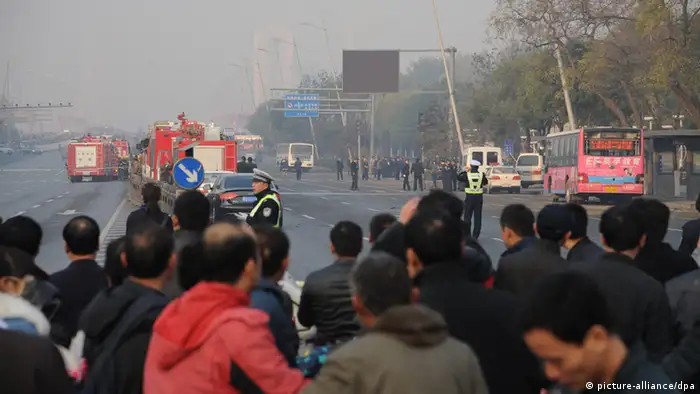 epa03937656 Onlookers watch policemen working at the site of explosions outside the provincial headquarters of China's ruling Communist Party in Taiyuan, Shanxi province, China, 06 November 2013. At least one person died and eight were injured by small explosions outside the Shanxi provincial headquarters of the ruling Communist Party in northern China police and state media said. EPA/YU TU CHINA OUT