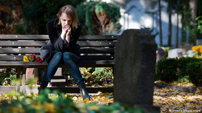 ILLUSTRATION - Eine Frau sitzt am 22.10.2013 auf einem Friedhof in Berlin auf einer Bank. Foto: Franziska Koark pixel