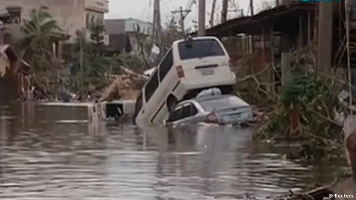 Vehicles are pictured stranded in a flooded street filled with debris after Typhoon Haiyan hit the central Philippine city of Tacloban, Leyte province in this still image from video November 8, 2013. Typhoon Haiyan, possibly the strongest storm ever to hit land, has devastated Tacloban, killing at least 100 people and destroying most houses in a surge of flood water and high winds, officials said on Saturday. The toll of death and damage is expected to rise sharply as rescue workers and soldiers reach areas cut off by the massive storm, now barrelling out of the Philippines towards Vietnam. REUTERS/GMA News via Reuters TV (PHILIPPINES - Tags: DISASTER TRANSPORT ENVIRONMENT) ATTENTION EDITORS - THIS IMAGE WAS PROVIDED BY A THIRD PARTY. FOR EDITORIAL USE ONLY. NOT FOR SALE FOR MARKETING OR ADVERTISING CAMPAIGNS. NO SALES. NO ARCHIVES. THIS PICTURE IS DISTRIBUTED EXACTLY AS RECEIVED BY REUTERS, AS A SERVICE TO CLIENTS. PHILIPPINES OUT. NO COMMERCIAL OR EDITORIAL SALES IN PHILIPPINES. MANDATORY CREDIT TO GMA NEWS