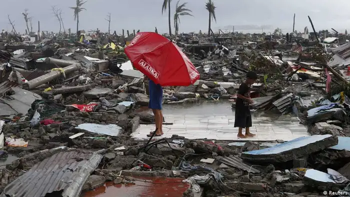 Residents stand on the ruins of their house amidst other destroyed houses after Super Typhoon Haiyan battered Tacloban city in central Philippines November 10, 2013. One of the most powerful storms ever recorded killed at least 10,000 people in the central Philippines province of Leyte, a senior police official said on Sunday, with coastal towns and the regional capital devastated by huge waves. Super typhoon Haiyan destroyed about 70 to 80 percent of the area in its path as it tore through the province on Friday, said chief superintendent Elmer Soria, a regional police director. REUTERS/Erik De Castro (PHILIPPINES - Tags: DISASTER ENVIRONMENT) -- eingestellt von haz