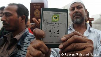 Foreign workers displays his passport as he waits outside a labour office Foto: REUTERS/Faisal Al Nasser