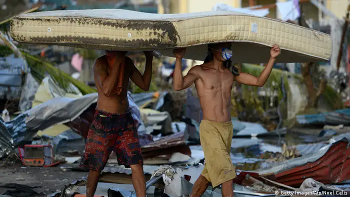 Residents carry a mattres taken from a hotel in Palo, eastern island of Leyte on November 10, 2013, three days after devastating Super Typhoon Haiyan hit the area on November 8. The death toll from a super typhoon that decimated entire towns in the Philippines could soar well over 10,000, authorities warned on November 10, making it the country's worst recorded natural disaster. AFP PHOTO / NOEL CELIS (Photo credit should read NOEL CELIS/AFP/Getty Images)