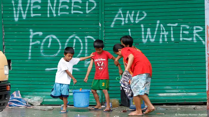 Children help to carry pails of drinking water as they walk past a graffiti calling for help after Typhoon Haiyan devastated Tacloban city, central Philippines November 12, 2013. Rescue workers tried to reach towns and villages in the central Philippines on Tuesday that were cut off by the powerful typhoon, fearing the estimated death toll of 10,000 could jump sharply, as relief efforts intensified with the help of U.S. military. REUTERS/Romeo Ranoco (PHILIPPINES - Tags: DISASTER ENVIRONMENT)