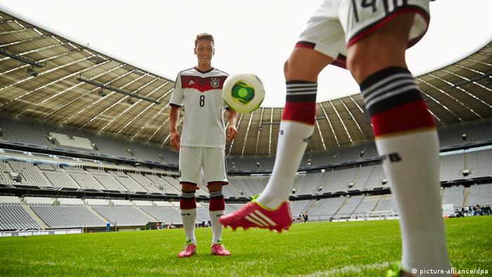 Der deutsche Fußballnationalspieler Mesut Özil (l) in Aktion im neuen Trikot der Nationalmannschaft von Ausrüster adidas für die Weltmeisterschaft 2014 in Brasilien in der Allianz Arena in München (Bayern) (Foto: Marcus Mueller-Saran/adidas/dpa)