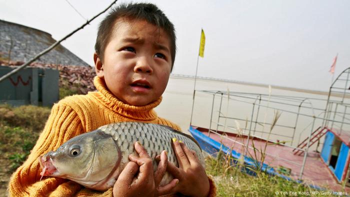 Yellow River, China: young boy holding dead fish