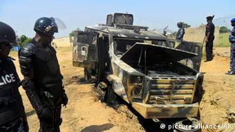 Soldaten stehen vor einem zerstörten Fahrzeug Foto: AP Photo
