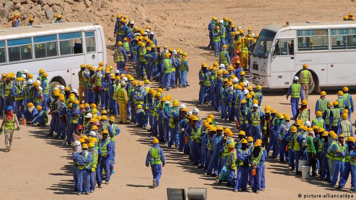 Foreign construction workers queue up for the bus back to their accommodation camp in Doha