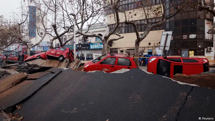 Overturned cars are seen on a damaged street after an explosion at a Sinopec Corp oil pipeline in Huangdao, Qingdao, Shandong Province November 23, 2013. Crude pipelines have been shut-off in the eastern Chinese oil hub of Qingdao pending safety checks a day after a leak triggered a huge explosion that killed 47 people, a refinery official and state media said on Saturday. REUTERS/Mo Yat (CHINA - Tags: DISASTER ENERGY) CHINA OUT. NO COMMERCIAL OR EDITORIAL SALES IN CHINA