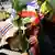گروهی از تظاهرکنندگان با گل در دست در روز دوشنبه (۲۵ نوامبر) در بانکوک در نزدیکی ساختمانی دولتی؛ آنان گل را به ماموران پلیس می‌دهند