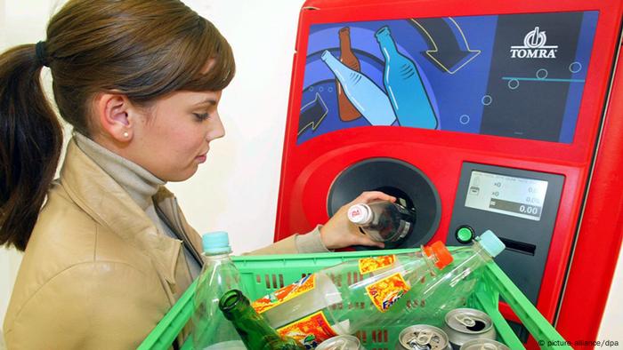 Una mujer introduce una botella usada en una máquina de reciclaje.