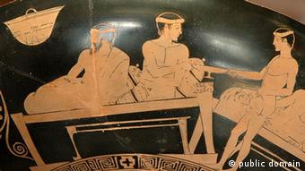 Ein antiker Teller, auf dem ein Mundschenk (rechts) zwei weiteren Personen Wein serviert