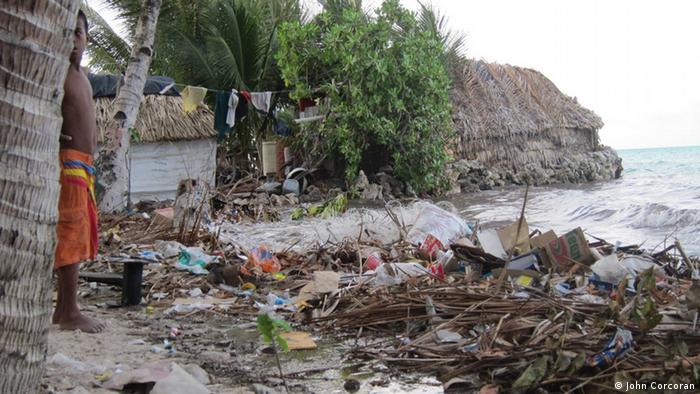 A child stands beside a sea wall in Kiribati