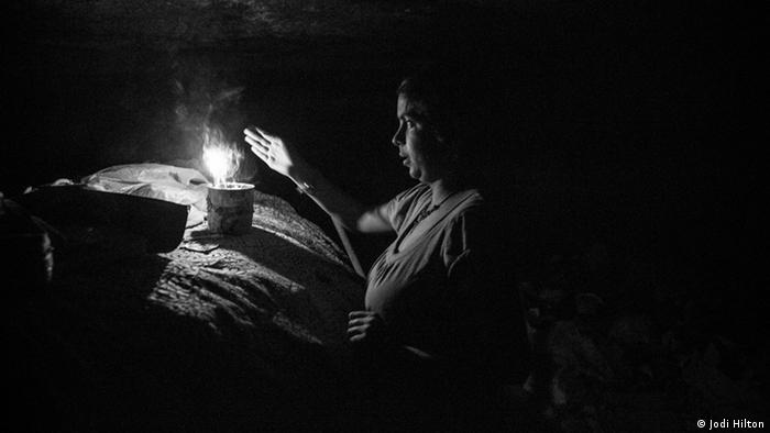 A young woman lights candles in the underground canal where she lives (photo: Jodi Hilton)