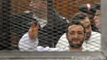 epa03999393 Egyptian activist Ahmed Douma flashes a victory sign behind dock bars during his trial in Cairo, Egypt, 22 December 2013 An Egyptian court on 22 December sentenced three prominent pro-democracy activists to three years in prison each, for holding an unauthorized protest. EPA/FOAD GARNOSY ELMAGD / ALMASRY ALYOUM BEST QUALITY AVAILABLE - EGYPT OUT