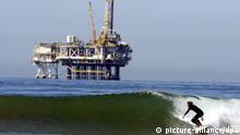 ARCHIV - A surfer rides a wave with an oil drilling rig in the background in Huntington Beach, California, USA 29 September 2013. Along southern California coast from Santa Barbara to Huntington Beach are a number of oil rigs in a petroleum rich region. EPA/MICHAEL NELSON (zu dpa: «Drill, baby, drill»: USA werden zum Ölförderer Nummer eins vom 25.12.2013) +++(c) dpa - Bildfunk+++