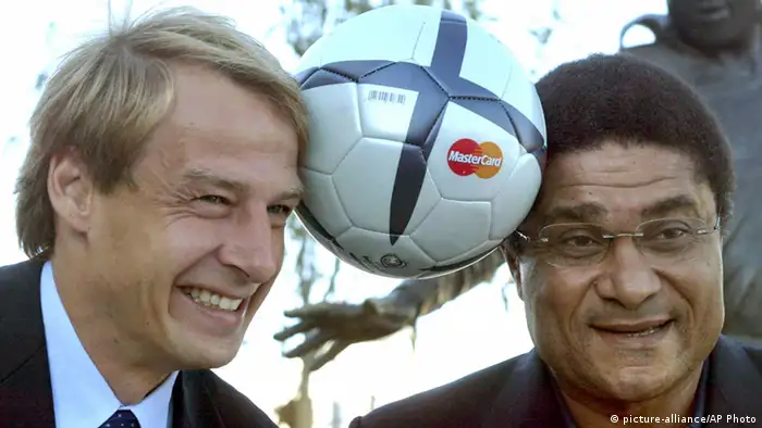 Deutschlands Stürmer- und Trainerstar Jürgen Klinsmann und Eusébio halten zur EM 2004 einen Fußball zwischen ihren Köpfen (Foto: picture-alliance/AP Photo)