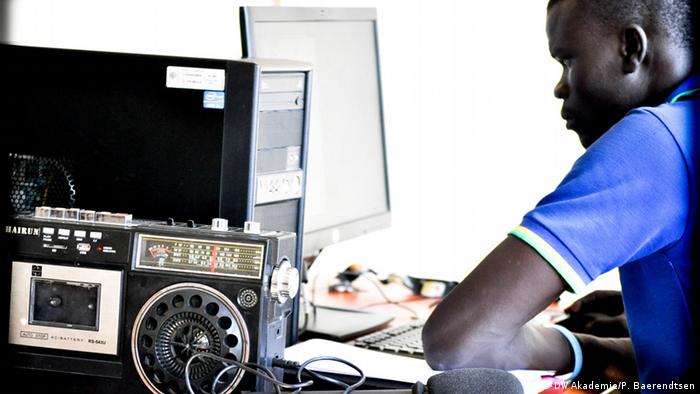 A man working at his desktop computer with a radio in the foreground.
