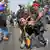 Two anti-government protestors in Thailand carry an injured fellow protestor following an explosive attack at the protest on January 17.