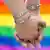 two men holding hands, gay pride flag