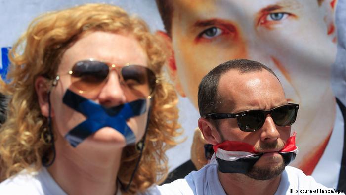 Protesters, with their mouths coverd with tape or bound by an Egyptian kerchief protest Egypt's detention of journalists.