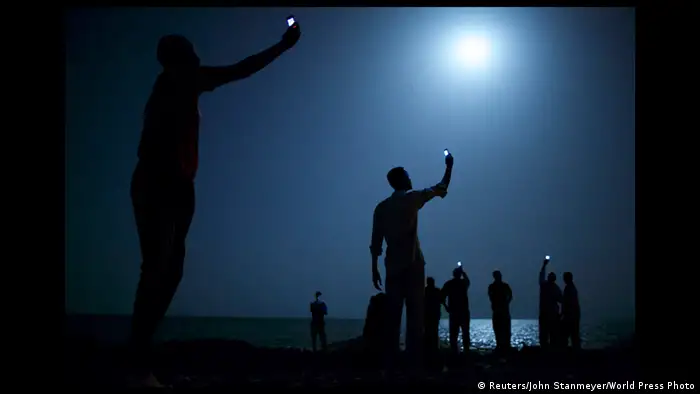 Migranten, die ihre Handys in den Himmel halten (Foto: World Press Photo 2014 John Stanmeyer /Reuters)