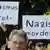 Teilnehmer einer Gedenkveranstaltung in Kassel für NSU-Opfer halten Schilder mit den Aufschriften "Nazis morden" und "Rassismus tötet" Foto: Uwe Zucchi (dpa)