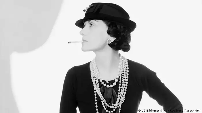 Coco Chanel wearing a hat and smoking a cigarette