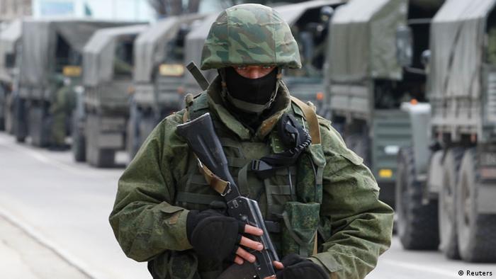 Masked soldier with gun standing in front of a line of army vehicles in the Crimean town of Balaclava in March 2014.