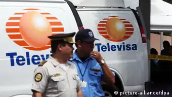 Two men in front of van with Televisa logo