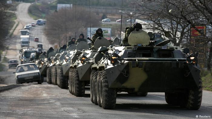 Mehrere Armeefahrzeuge fahren auf einer Straße Kolonne, Soldaten schauen aus den Luken