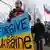 Участница протестной акции в Москве в марте 2014 года с плакатом в виде украинского флага и надписи на английском "Прости нас, Украина"