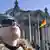 Eine Frau mit Mütze und Sonnenbrille schaut vor dem Berliner Reichstag in den Himmel