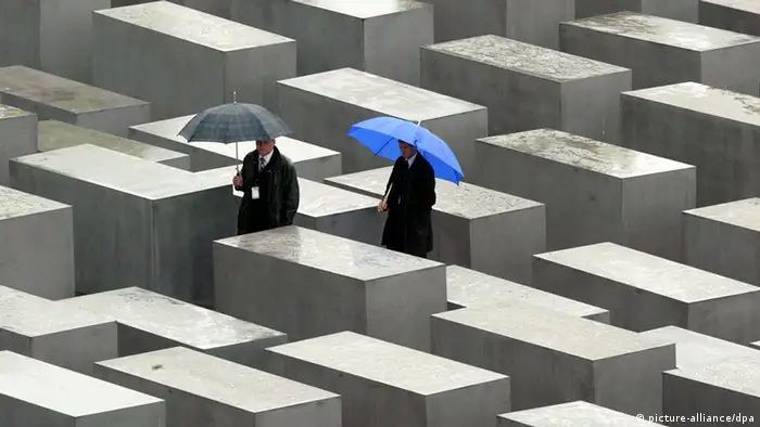People walk between the concrete pillars during the inauguration of the Holocaust memorial site in Berlin May 10, 2005