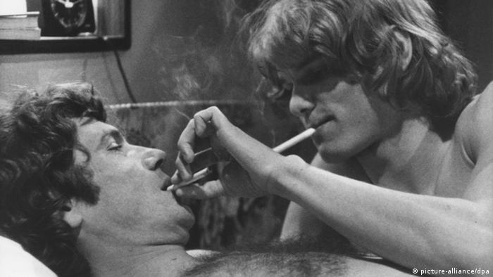 Film still The Consequence, two men with naked upper bodies in bed, smoking 