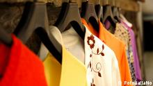 Auf Kleiderbügeln hängen hintereinander Kleidungsstücke in verschiedenen Farben.