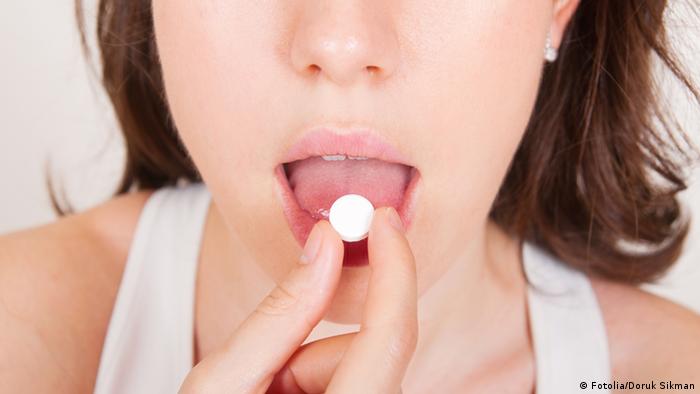 Foto simbólica de una mujer con una pastilla en la boca