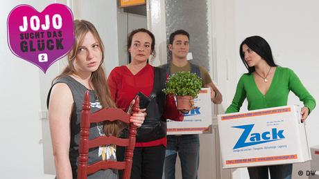 Jojo, Reza, Lotta und ihre Mutter stehen in der WG-Wohnung und tragen Umzugskisten und Möbel. (DW)