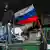 Человек в маске рядом с российским флагом