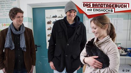 Zwei Musiker der Band EINSHOCH6 stehen neben einer Tierheim-Mitarbeiterin, die ein Kaninchen auf dem Arm hält.