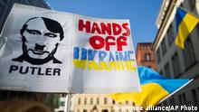 Activists holding placards depicting Russian President Vladimir Putin as Adolf Hitler reading Putler and hands off Ukraine in front of the Ukrainian embassy during a solidarity demonstration for the Ukraine and protesting the buildup of Russia¿s military presence in Crimea, in Berlin, Germany, Sunday, March 9, 2014. (AP Photo/Gero Breloer) pixel