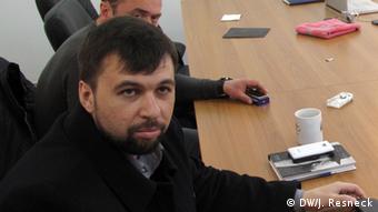 Denis Pushilin sits at a table with other individuals.
