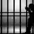 Das scherenschnittartige Schattenbild eines Mannes hinter Gitterstäben symbolisiert die Inhaftierung.
