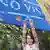 Девушка держит в вытянутых руках паспорт Молдавии на фоне плаката "Виз больше не надо"