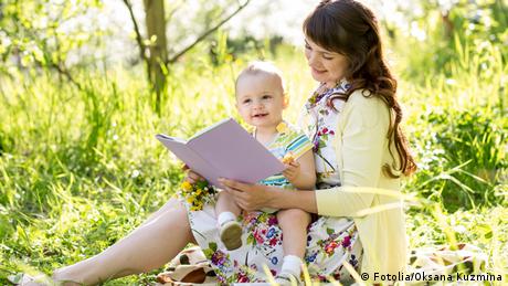 Symbolbild Mutter mit Baby Buch lesen vorlesen Natur 