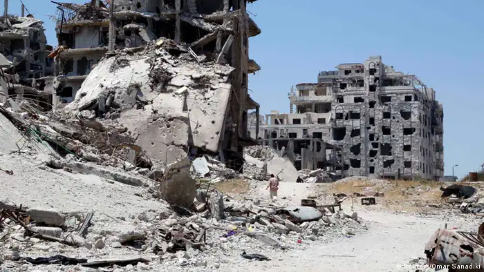 Men walk past damaged buildings in Homs, Syria in May 2014 (Reuters/Omar Sanadiki)