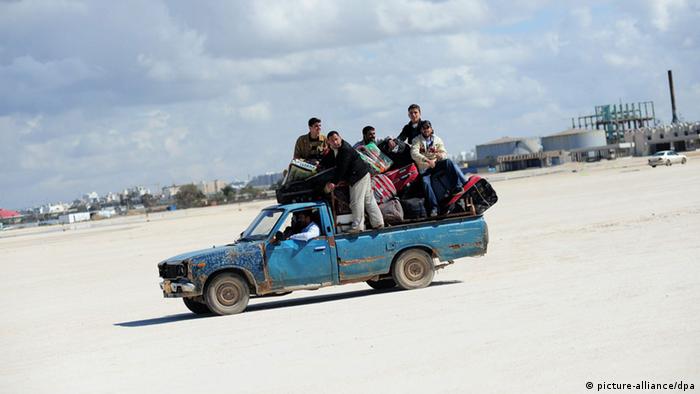 Syrian refugees in a car on the sand