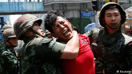 A man cries with pain as he is arrested by a soldier in Thailand 